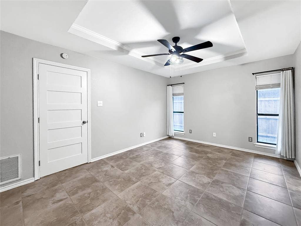 305 N Cottonbelt Avenue, Wylie, TX 75098 Tray ceiling with a central multi-blade ceiling fan, neutral tile flooring, and a solid-core four-panel interior door