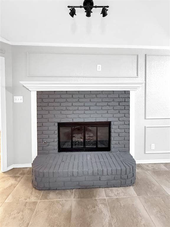 305 N Cottonbelt Avenue, Wylie, TX 75098 Fireplace featuring a grey-painted brick surround and raised hearth, capped with a white crown molding mantel, complemented by decorative wall molding and triple-track matte black ceiling lighting
