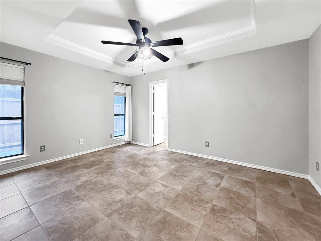 305 N Cottonbelt Avenue, Wylie, TX 75098 Interior room featuring a tray ceiling, ceiling fan with integrated lighting, tile flooring, and windows with neutral roller shades