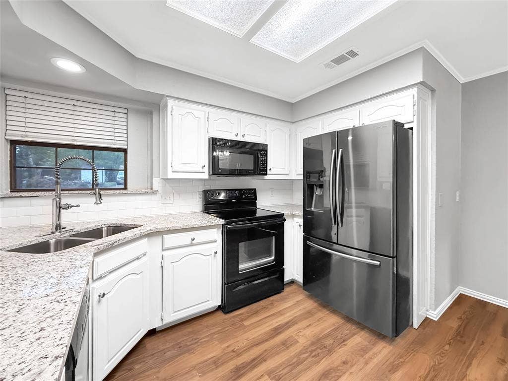 305 N Cottonbelt Avenue, Wylie, TX 75098 Kitchen featuring white cabinetry, stone-finish countertops, subway tile backsplash, stainless steel finish refrigerator, and wood-finish flooring