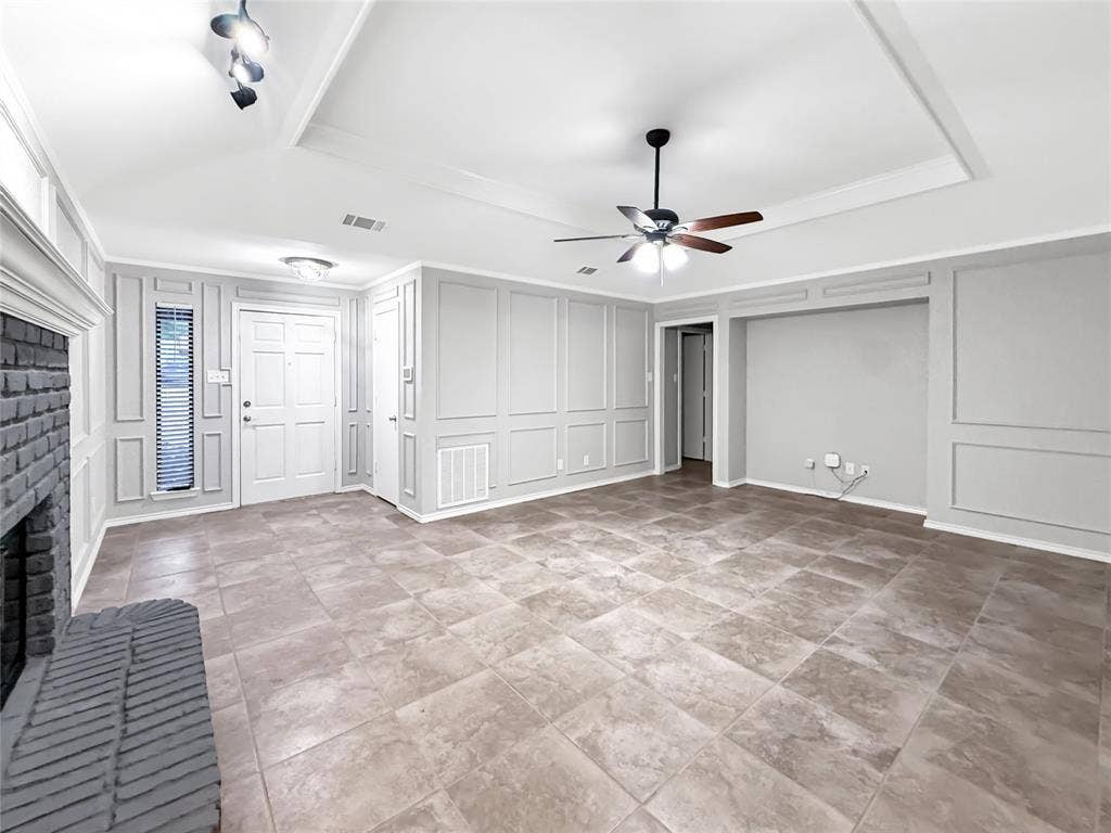 305 N Cottonbelt Avenue, Wylie, TX 75098 Tray ceiling with recessed lighting, full-wall decorative wainscoting, large-format tile flooring, brick-surround fireplace, and central ceiling fan with integrated light fixture
