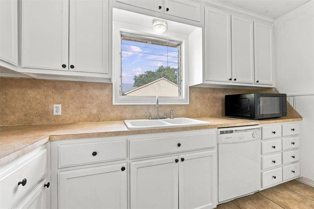 White cabinetry featuring flat-panel hardware, solid surface countertops, a dual-basin sink, and a built-in dishwasher