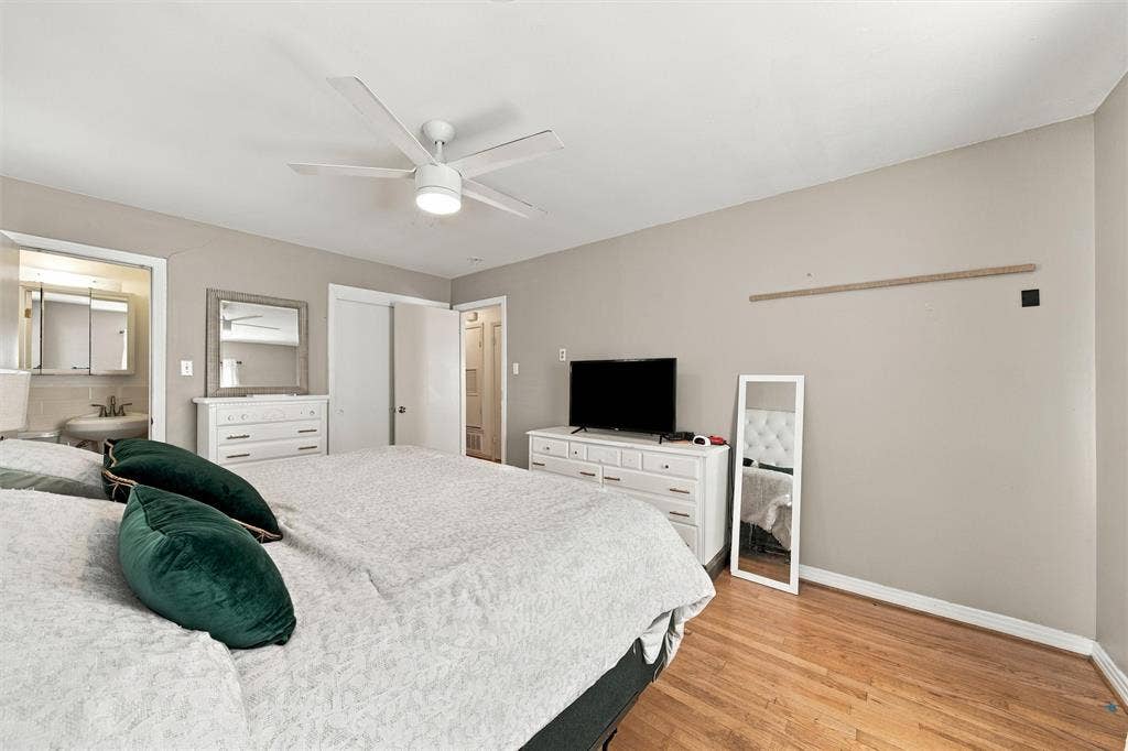 Room featuring wood-finish flooring, a neutral paint palette, and a white ceiling fan with integrated lighting