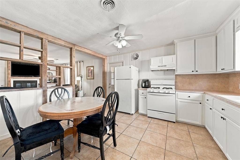 Kitchen featuring white cabinetry, tile flooring, and an open timber partition