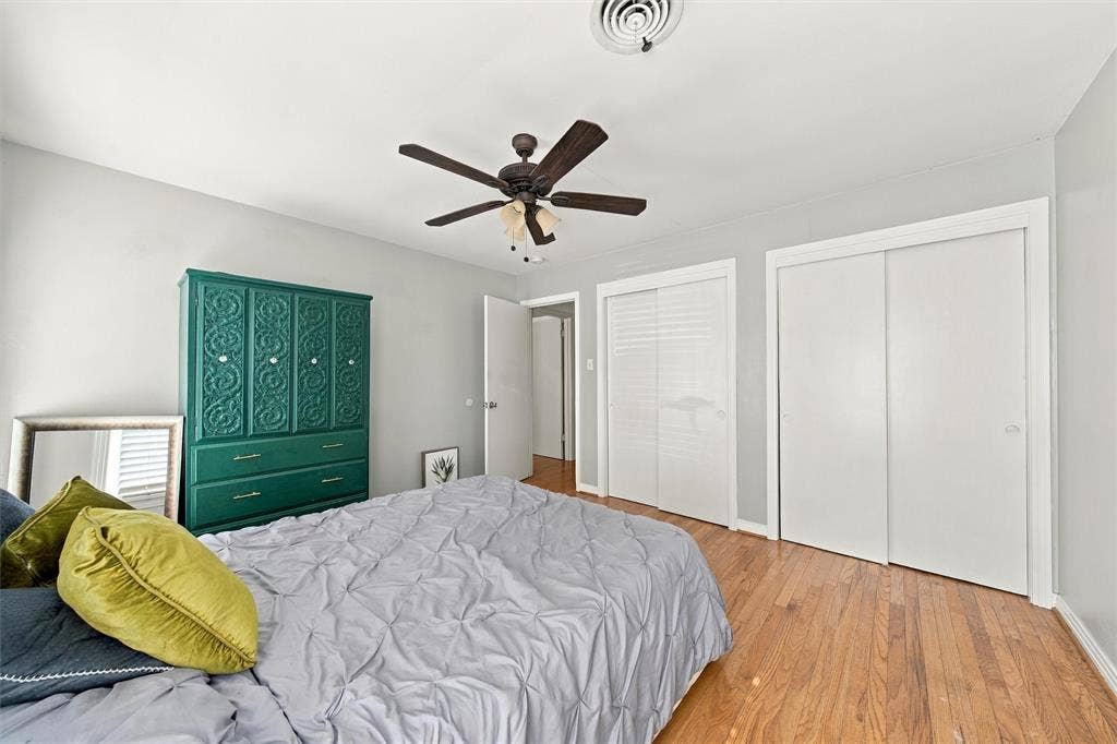 Wood-finish flooring, dual sliding-door closets, and a ceiling fan with integrated lighting