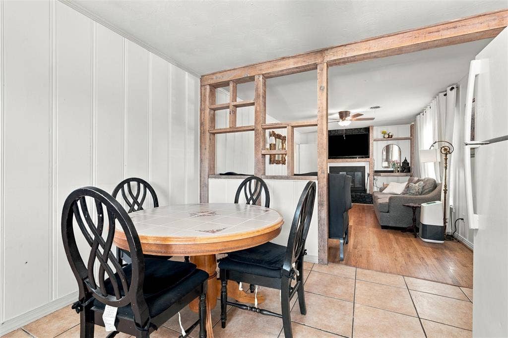 Interior featuring a decorative wood-framed open partition, wood-finish flooring, ceramic tile flooring, and a stone-surround fireplace