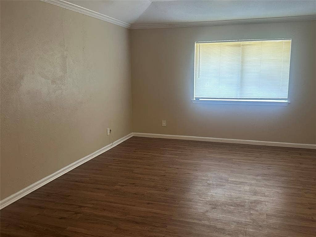 Interior space featuring wood-finish flooring, neutral wall paint, and a window with horizontal blinds