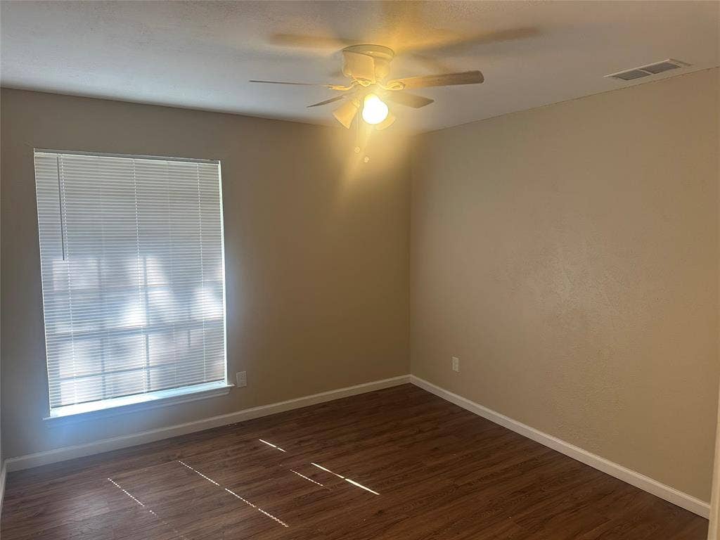 Room featuring wood-finish flooring, a neutral wall palette, window with integrated blinds, and a ceiling fan with light fixture