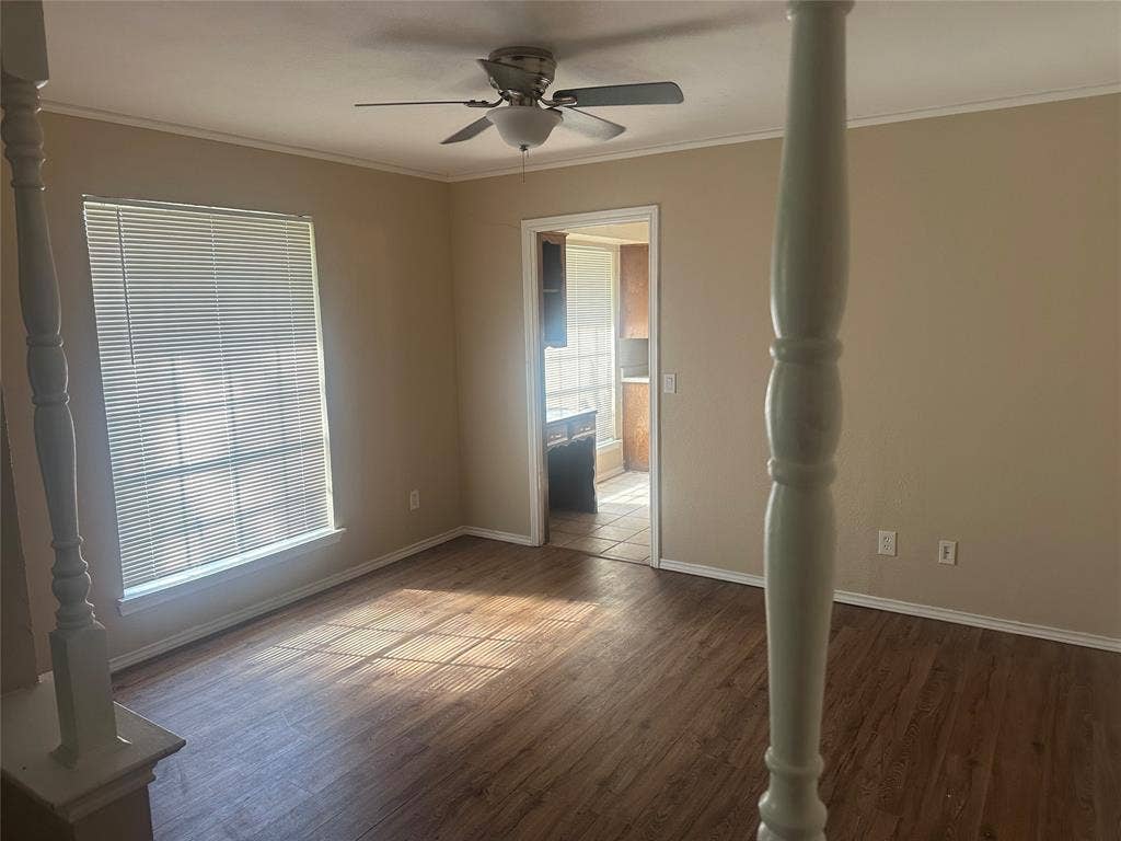 Interior room featuring wood-finish flooring, a ceiling fan, and prominent decorative columns