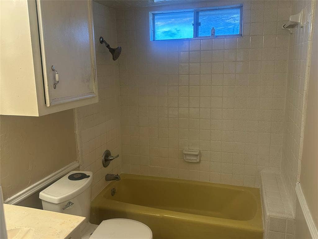 Bathroom featuring a soaking tub, wall-mounted shower head, tiled shower surround, built-in medicine cabinet, and slider window