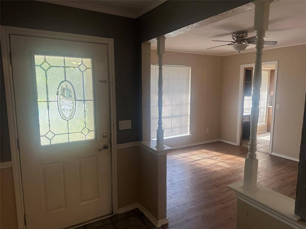 Entryway featuring a solid door with decorative glass paneling, wood-finish flooring, and white spindle columns on a half-wall partition