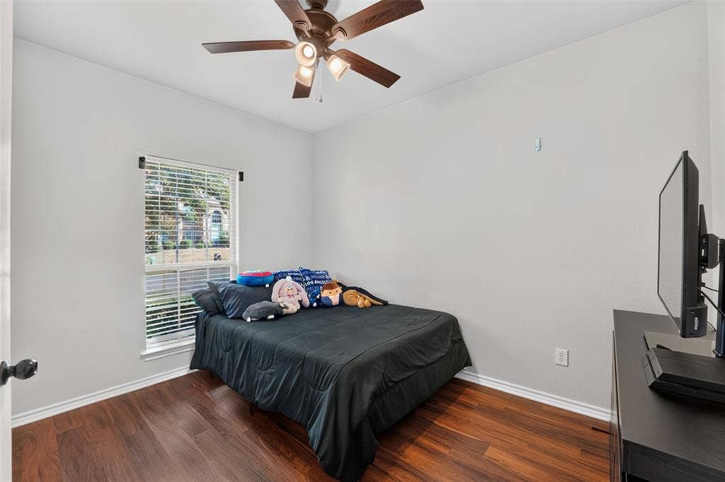 Room featuring wood-finish flooring, a neutral wall color palette, a single-pane window, and a ceiling fan with integrated lighting