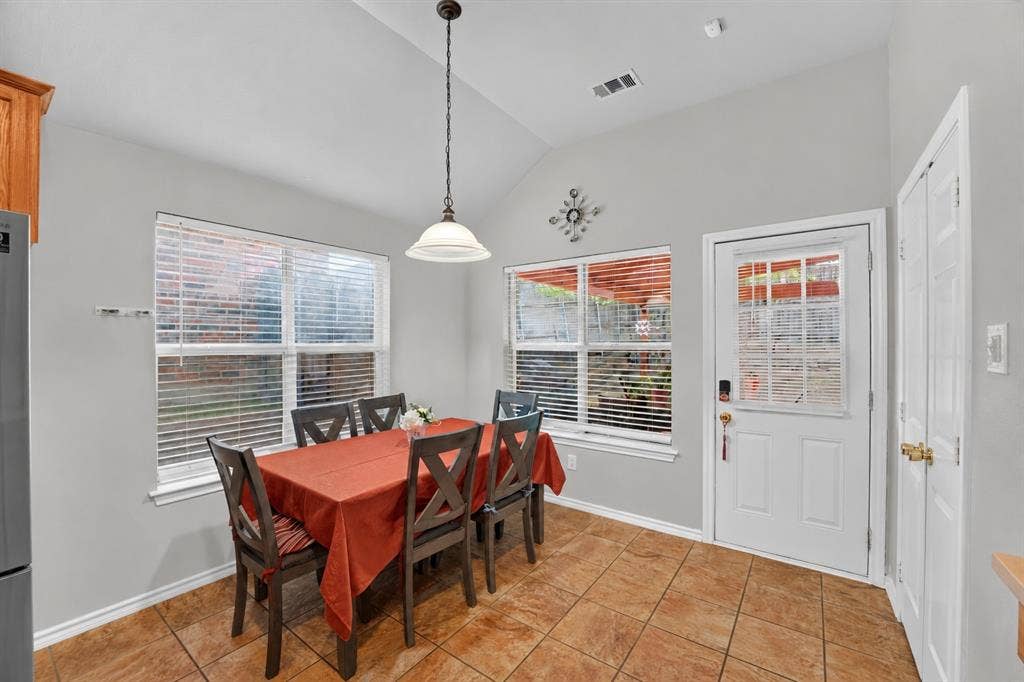 Vaulted ceilings, neutral wall tones, ceramic tile flooring, single-pendant overhead lighting, and multi-pane glass entry door