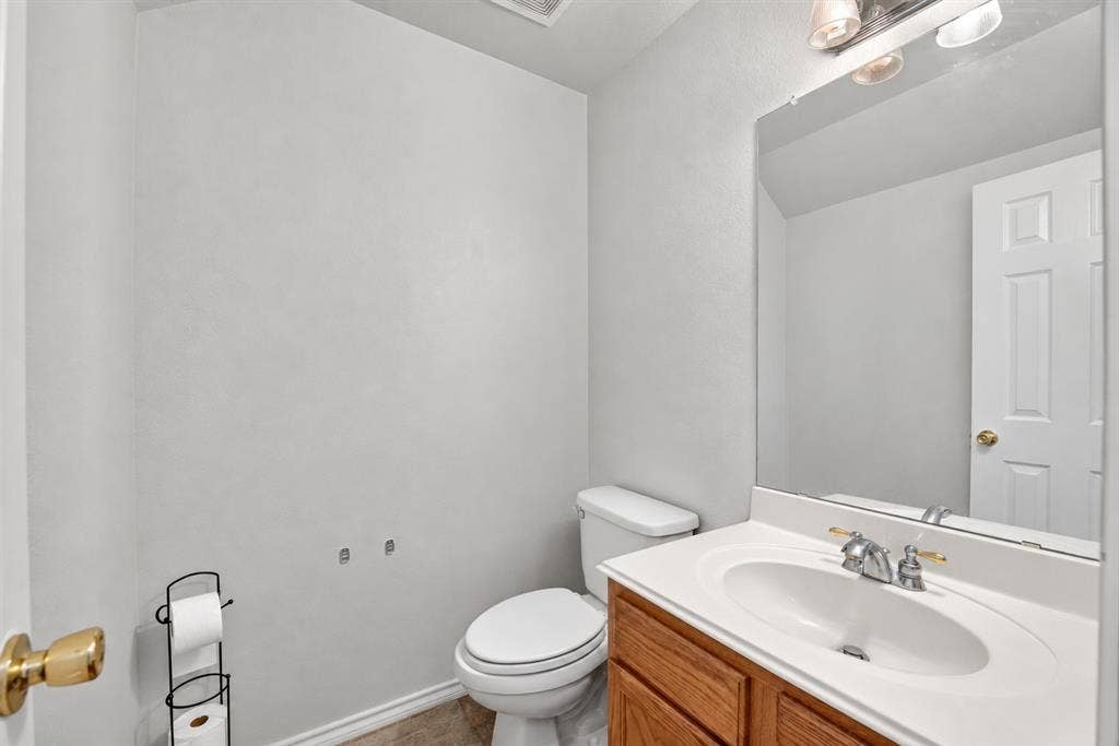 Wood-cabinet vanity with a white countertop, integrated sink, chrome-finish faucet, and a large wall-mounted mirror