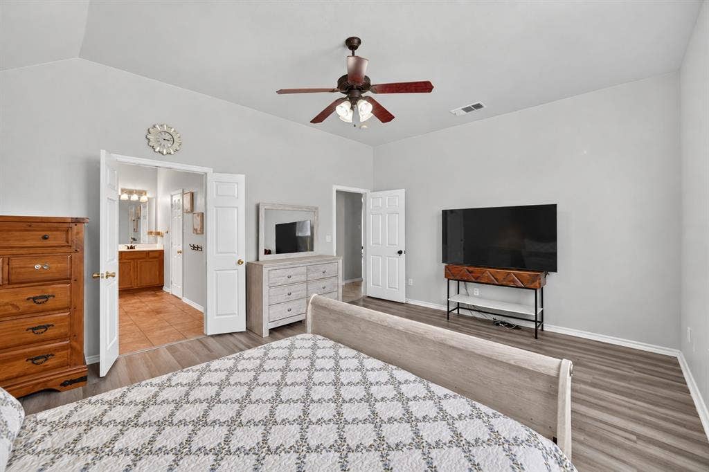Vaulted ceiling with an integrated multi-blade ceiling fan and wood-finish flooring