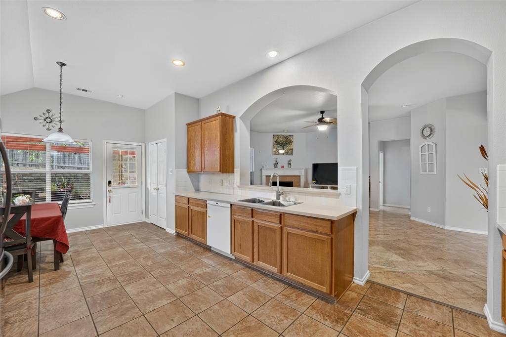 Kitchen featuring wood cabinetry, recessed lighting, tile flooring, and a large arched pass-through window with a dual-basin sink