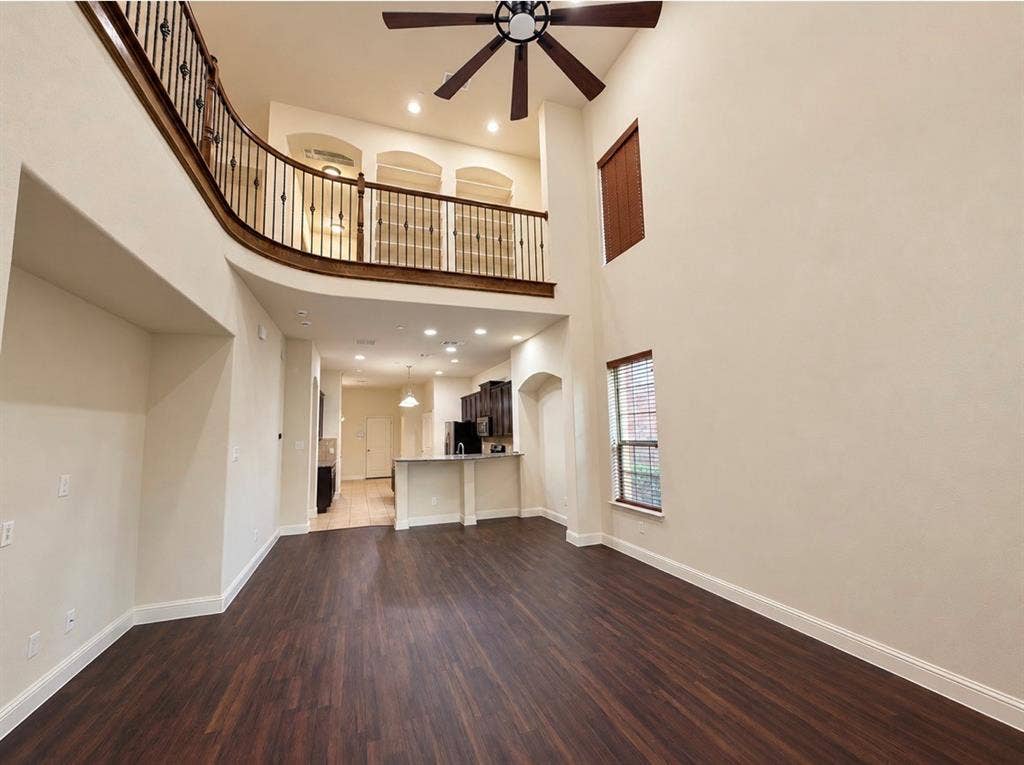8616 Naomi Street, Plano, TX 75024 Double-height ceiling featuring a ceiling fan, wood-finish flooring, and an elevated mezzanine with dark metal balusters