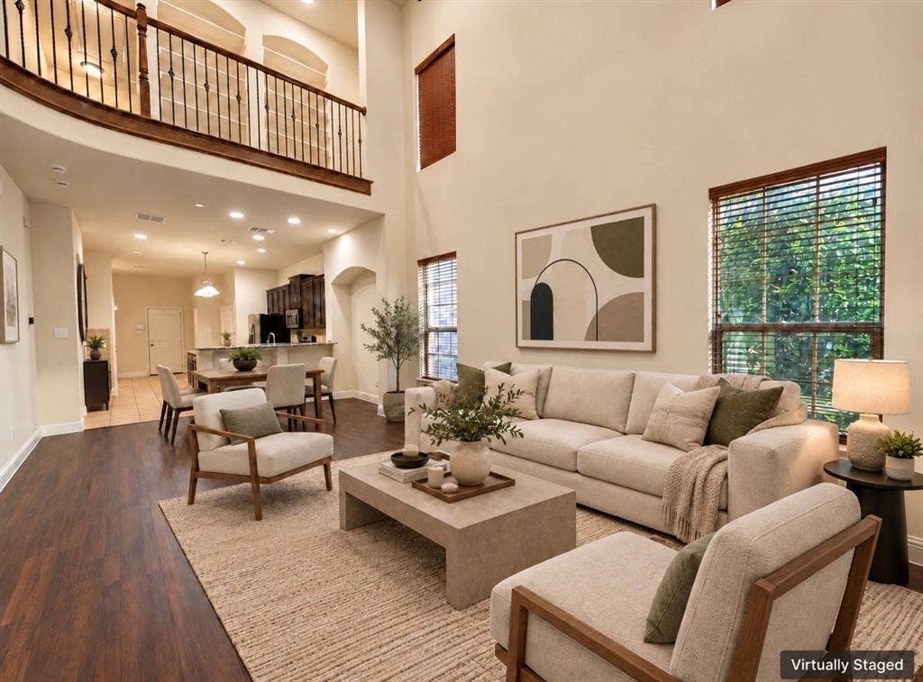 8616 Naomi Street, Plano, TX 75024 Two-story living area featuring expansive ceilings, wood-finish flooring, recessed lighting, and a metal-railed mezzanine balcony