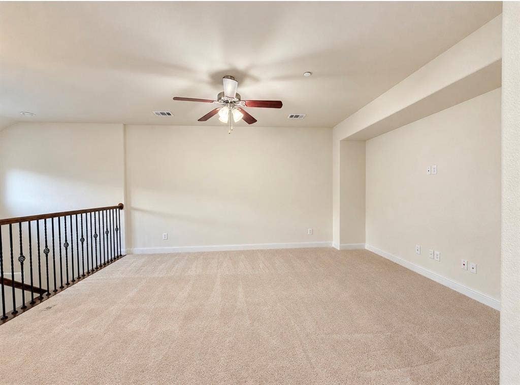8616 Naomi Street, Plano, TX 75024 Open living area featuring wall-to-wall carpeting, high ceilings, a ceiling fan with integrated lighting, and a wrought-iron staircase railing