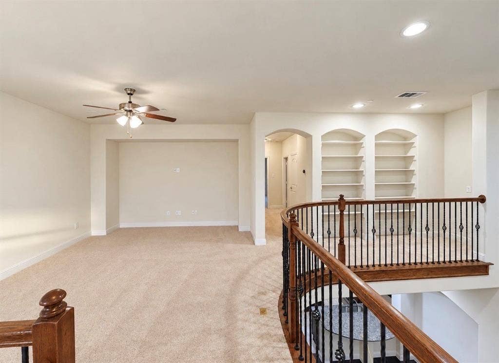 8616 Naomi Street, Plano, TX 75024 Curved balcony featuring metal balusters and a wood handrail, built-in recessed shelving, and integrated ceiling lighting