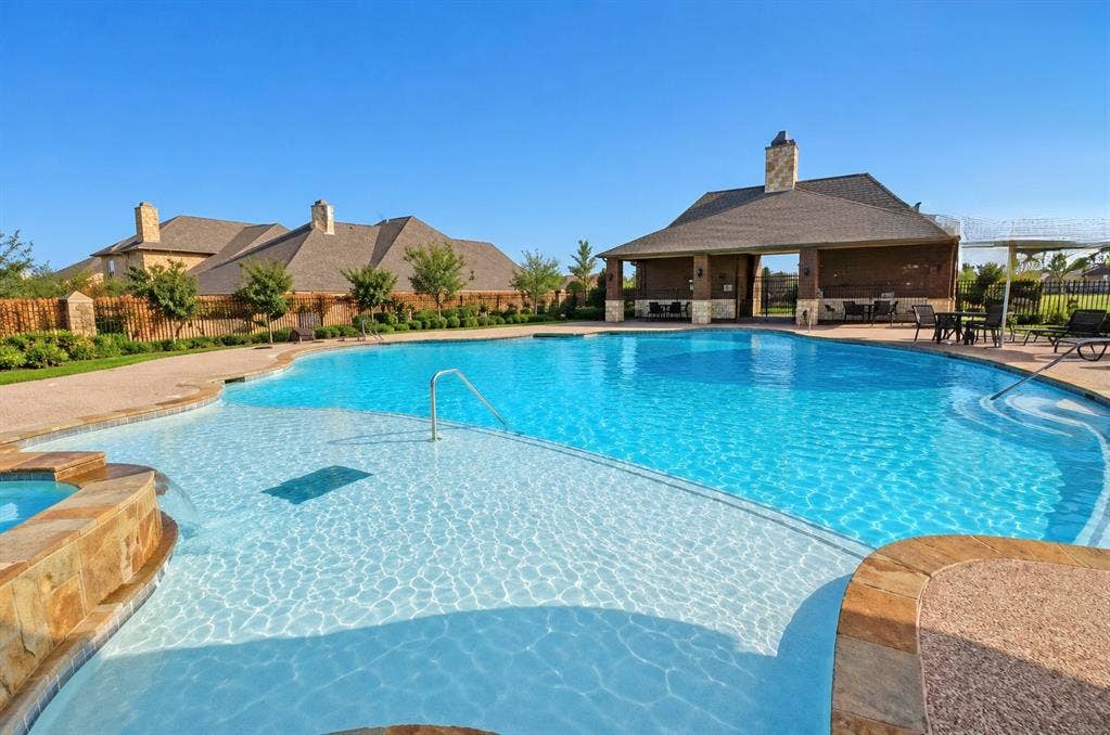 8616 Naomi Street, Plano, TX 75024 Swimming pool with stone-finished edging, integrated spa, and covered pavilion featuring a stone hearth