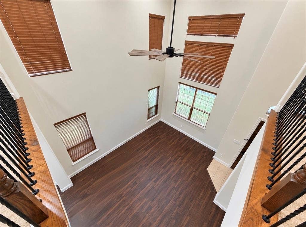 8616 Naomi Street, Plano, TX 75024 Double-height ceiling, wood-finish flooring, multi-level windows, wrought iron railing with wood accents, and ceiling fan