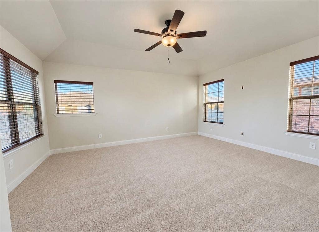 8616 Naomi Street, Plano, TX 75024 Neutral-toned room featuring a tray ceiling, wall-to-wall carpeting, multiple windows with blinds, and a central ceiling fan with an integrated light fixture