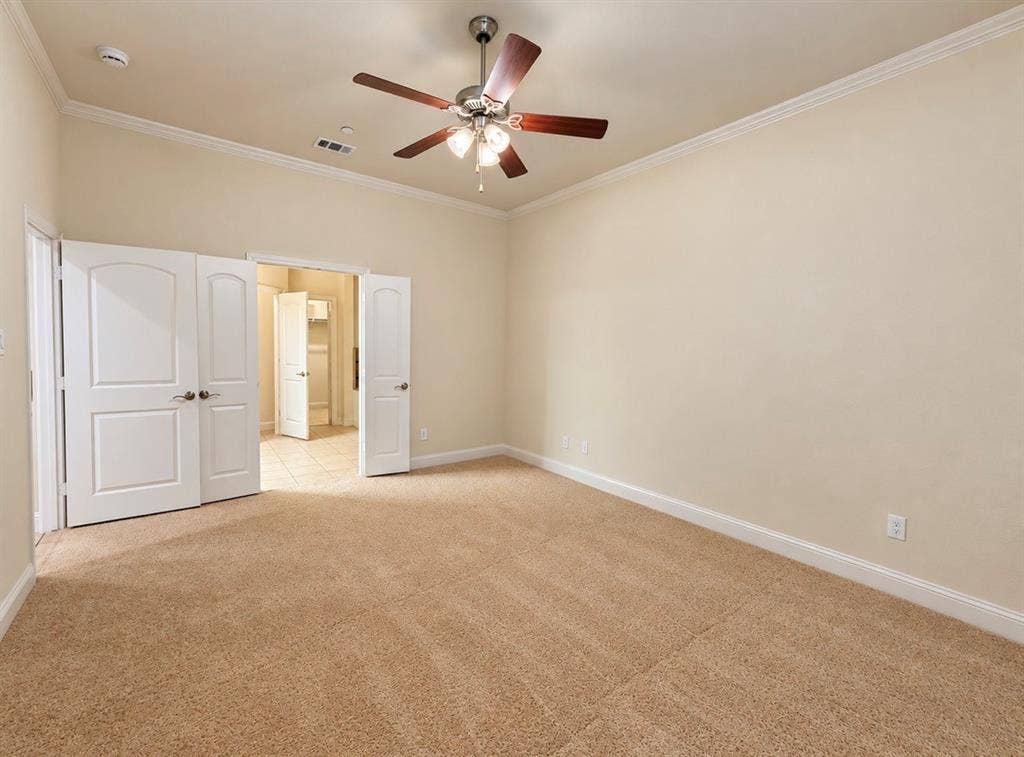 8616 Naomi Street, Plano, TX 75024 Room featuring neutral carpeting, crown molding, multi-panel arched doors, and a ceiling fan with integrated lighting