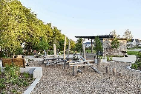 9096 Phoebe Road, Frisco, TX 75035 Outdoor recreational area featuring wood-beam climbing structures, integrated concrete bench seating, wood chip surfacing, and a stone-clad pavilion