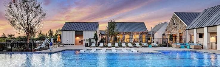 9096 Phoebe Road, Frisco, TX 75035 Swimming pool featuring a Baja shelf, stone and vertical siding exterior, metal roofing, and paved deck