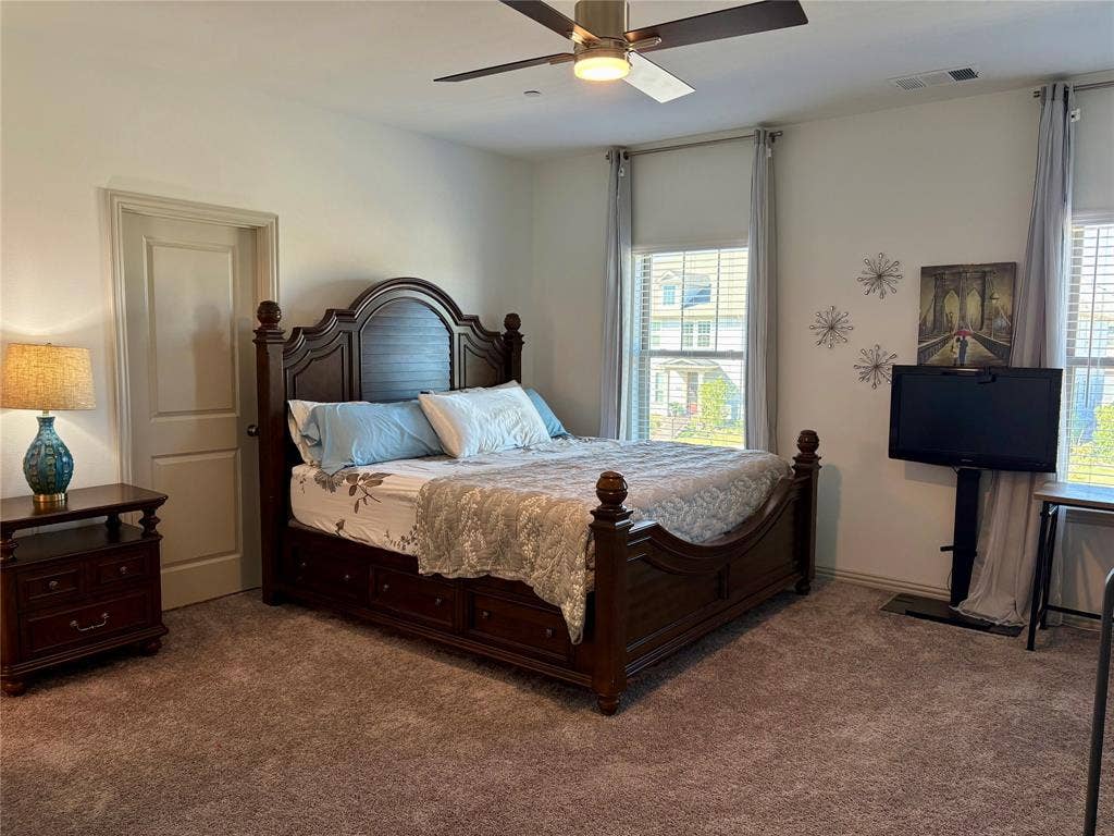 9096 Phoebe Road, Frisco, TX 75035 Spacious bedroom featuring wall-to-wall carpeting, dual windows, and an integrated ceiling fan with central light fixture