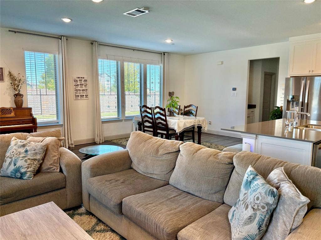 9096 Phoebe Road, Frisco, TX 75035 Open-concept living space featuring high ceilings with recessed lighting, large windows with natural illumination, and a kitchen island with stone-surface countertop
