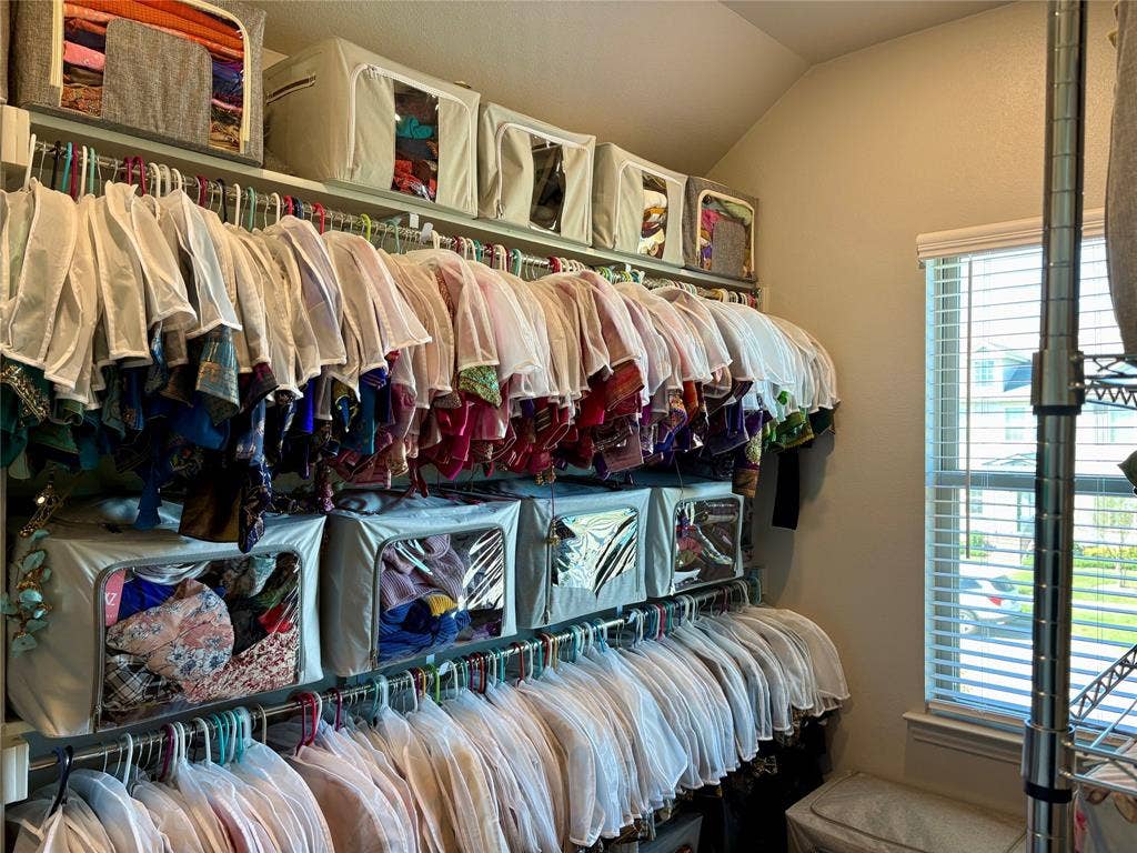 9096 Phoebe Road, Frisco, TX 75035 Multi-tier metal closet shelving system featuring horizontal hanging rods and adjustable window blinds