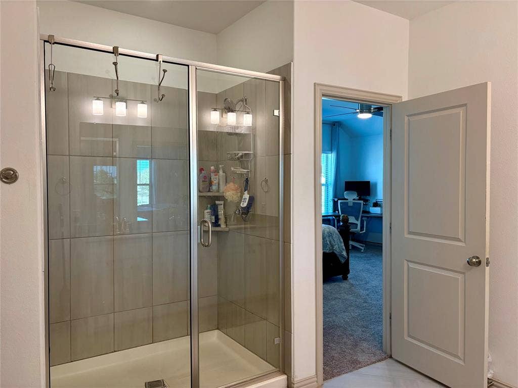 9096 Phoebe Road, Frisco, TX 75035 Walk-in shower with floor-to-ceiling ceramic tile surround, glass enclosure, chrome hardware, and a built-in corner shelving unit