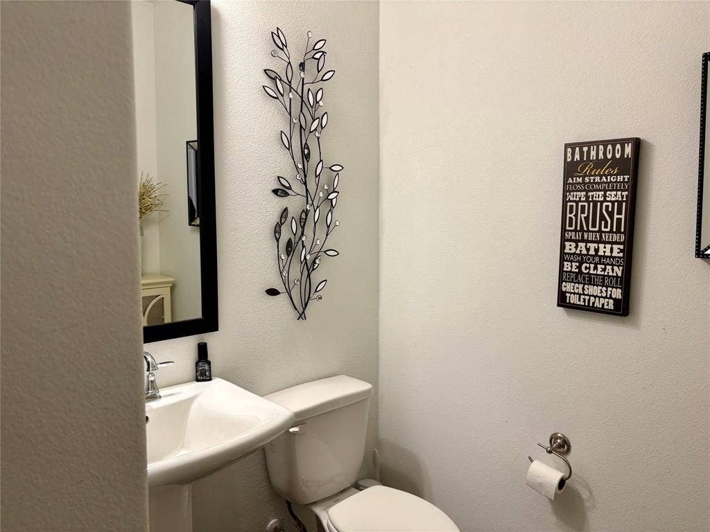 9096 Phoebe Road, Frisco, TX 75035 Wall-mounted rectangular mirror with a black frame, pedestal sink with a chrome finish faucet, and polished chrome toilet paper holder