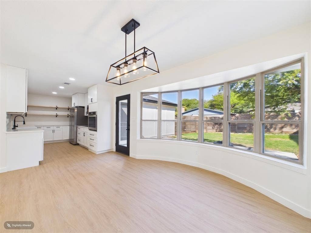 Open concept area featuring wood-finish flooring, a curved window wall, custom white cabinetry, open shelving, and an industrial-style geometric pendant light