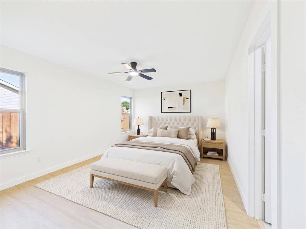 Neutral interior space featuring wood-finish flooring, dual-pane windows, and a ceiling-mounted light fixture with fan