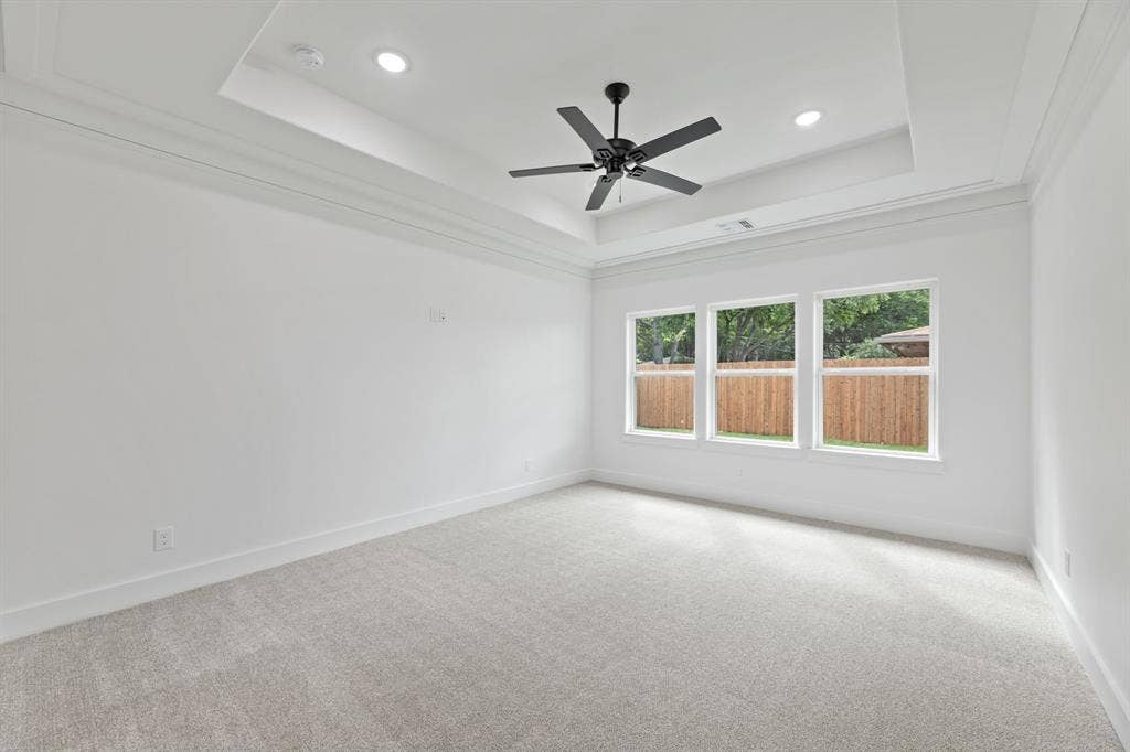 Empty room featuring a tray ceiling, baseboards, and light colored carpet