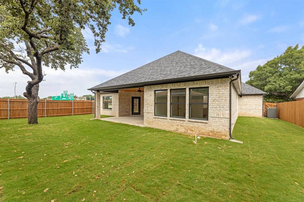 Back of property with a lawn, a shingled roof, a fenced backyard, and a patio area