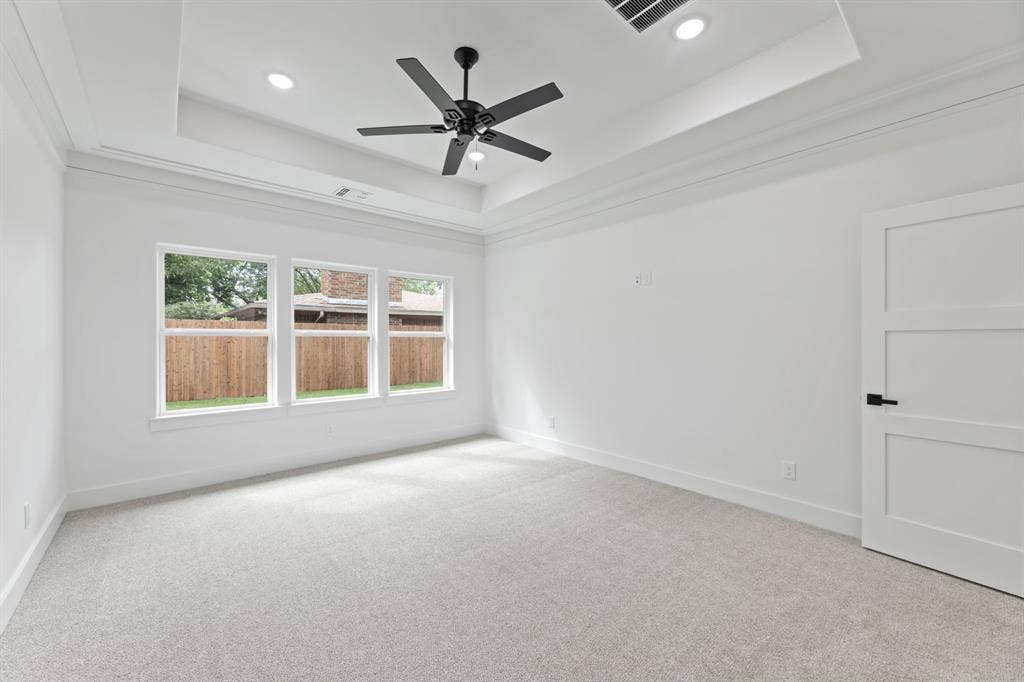 Carpeted spare room with visible vents, a tray ceiling, baseboards, and recessed lighting