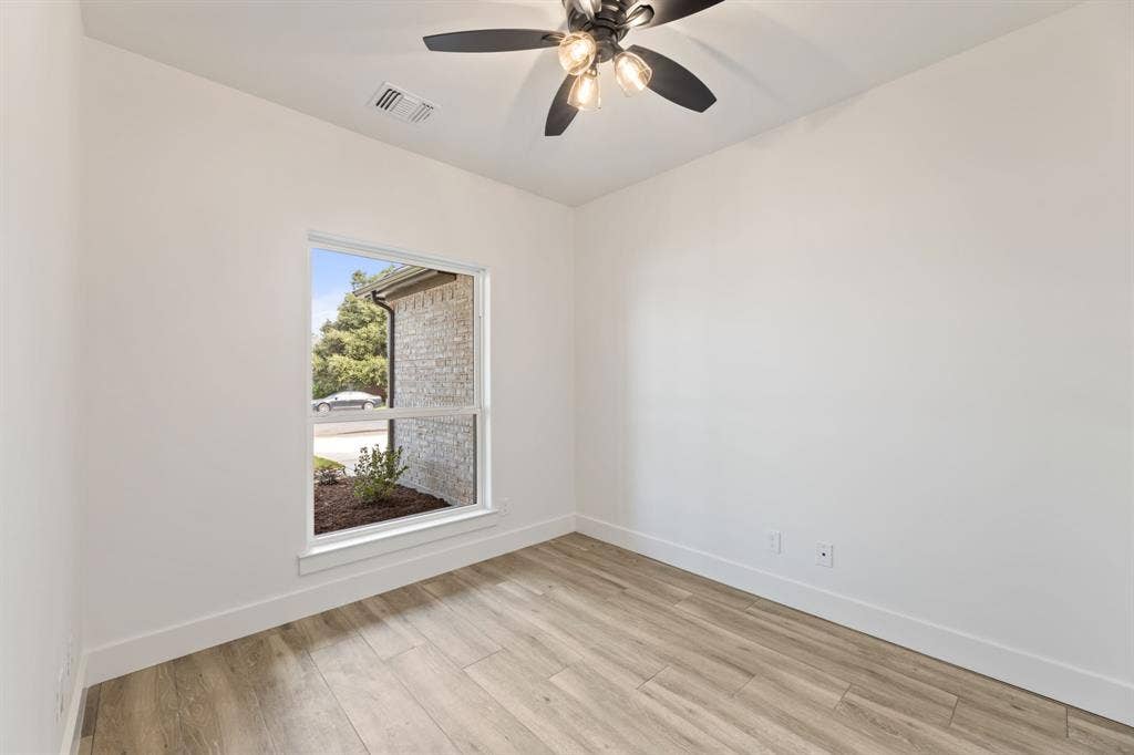 Empty room with a ceiling fan, light wood-style flooring, baseboards, and visible vents