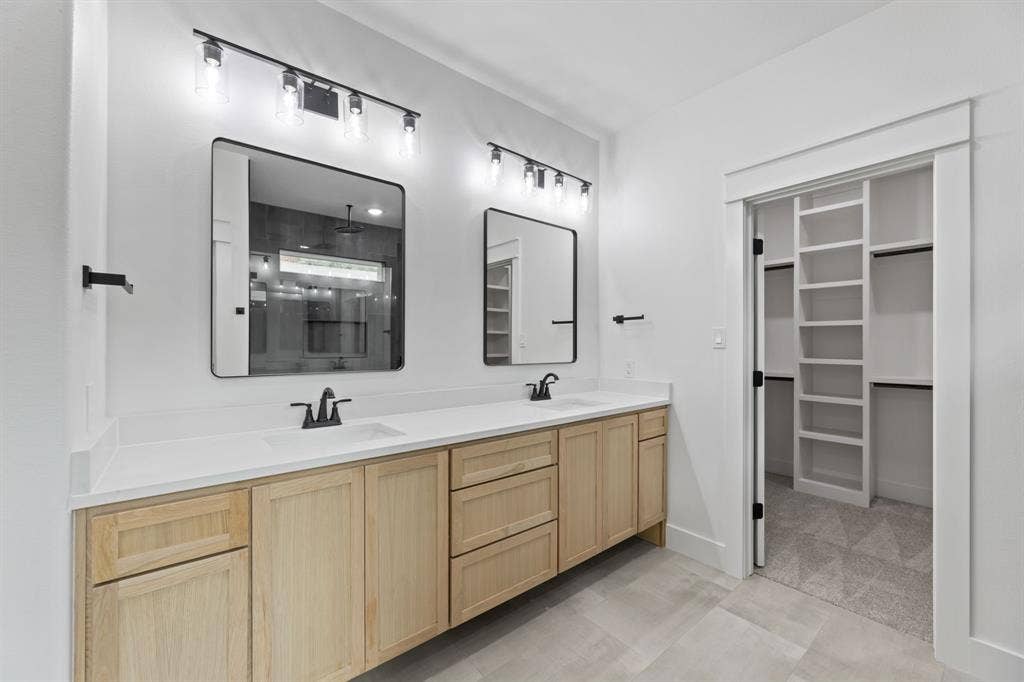 Bathroom featuring double vanity, a sink, and a walk in closet
