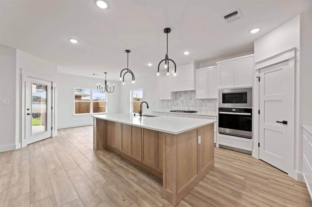 Kitchen with light countertops, stainless steel oven, tasteful backsplash, gas cooktop, and built in microwave
