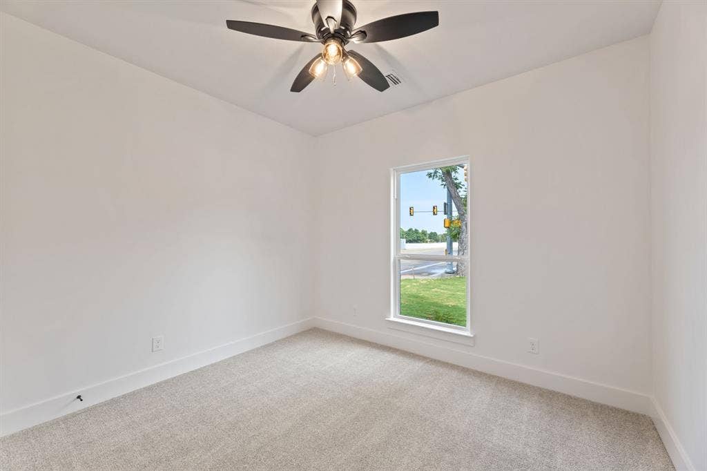 Unfurnished room featuring baseboards, visible vents, a ceiling fan, and light colored carpet