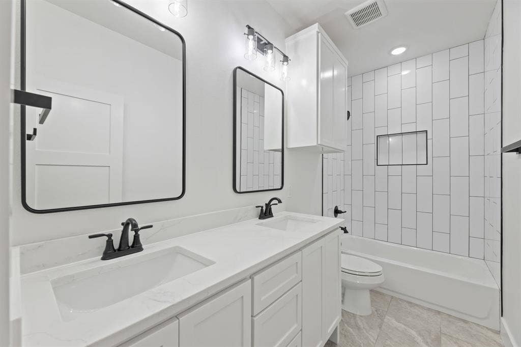 Bathroom with visible vents, a sink, toilet, and double vanity