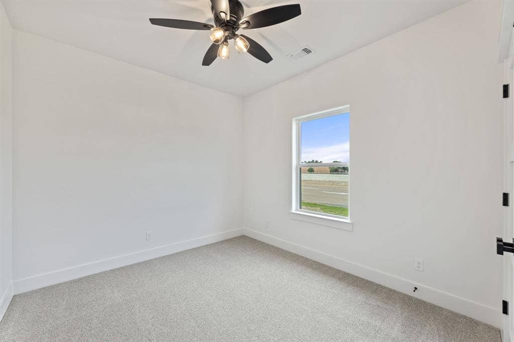 Unfurnished room with a ceiling fan, baseboards, light colored carpet, and visible vents