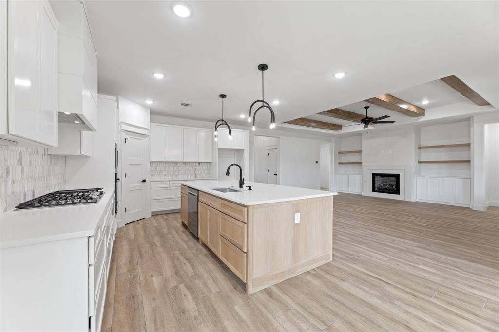 Kitchen featuring light wood finished floors, ceiling fan, appliances with stainless steel finishes, light brown cabinets, and a sink