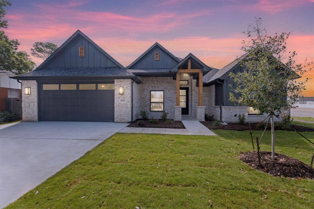 View of front of property featuring concrete driveway, board and batten siding, a shingled roof, a garage, and a yard