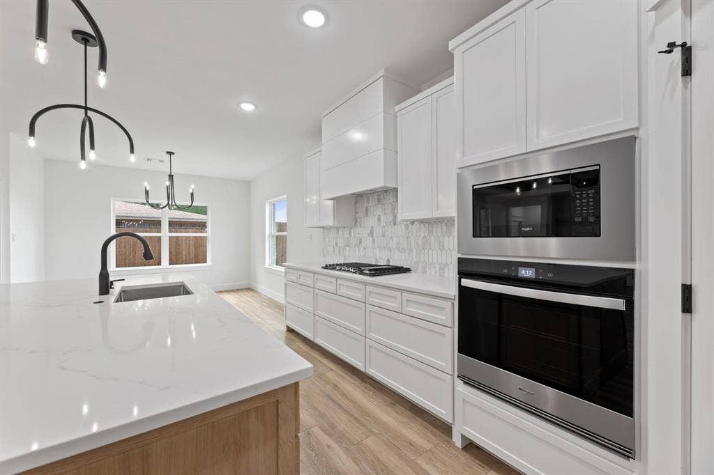 Kitchen featuring decorative backsplash, a sink, stainless steel gas stovetop, light wood-style floors, and wall oven