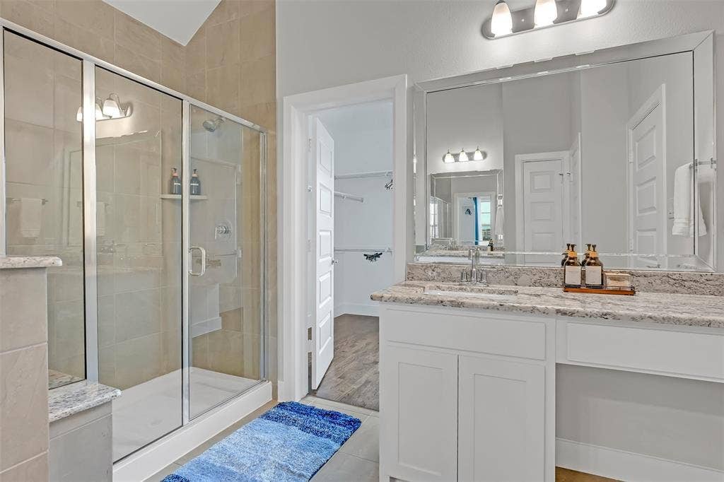 Full bath with vanity, a stall shower, and a walk in closet